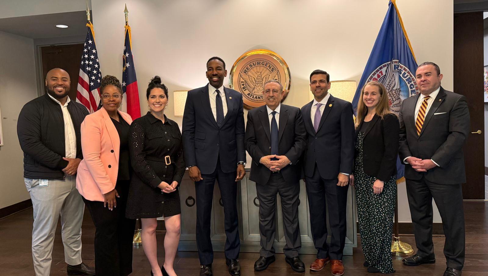 مجموعة من الأشخاص يلتقطون صورة جماعية أمام أعلام الولايات المتحدة، ضمن فعاليات رياضية.