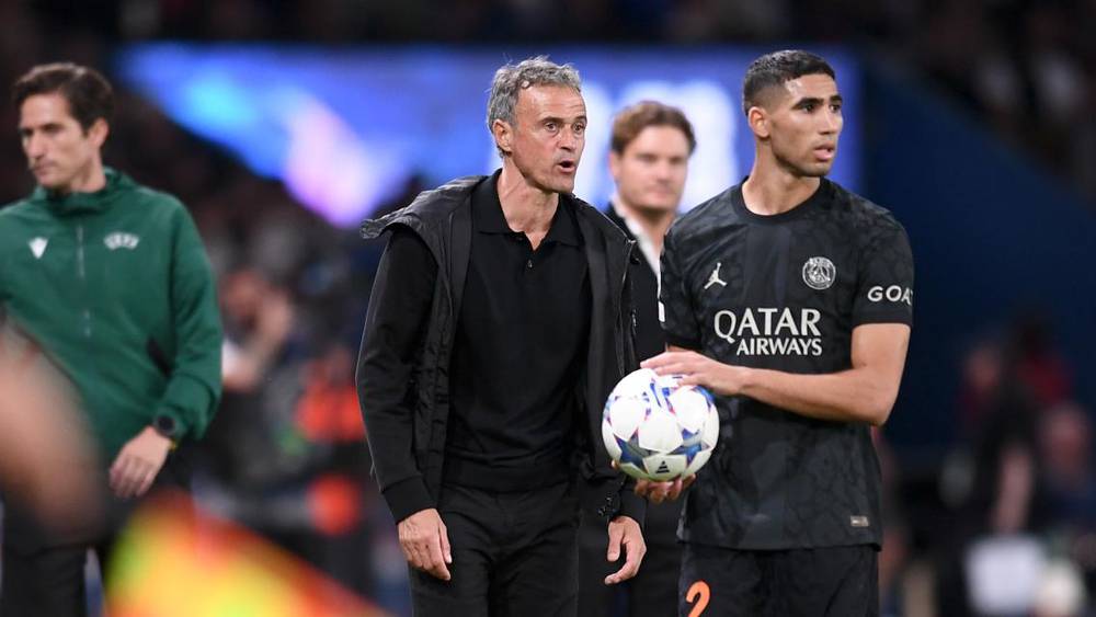 المدرب لويس إنريكي يقف بجانب لاعب كرة القدم أشرف حكيمي في ملعب كرة قدم.