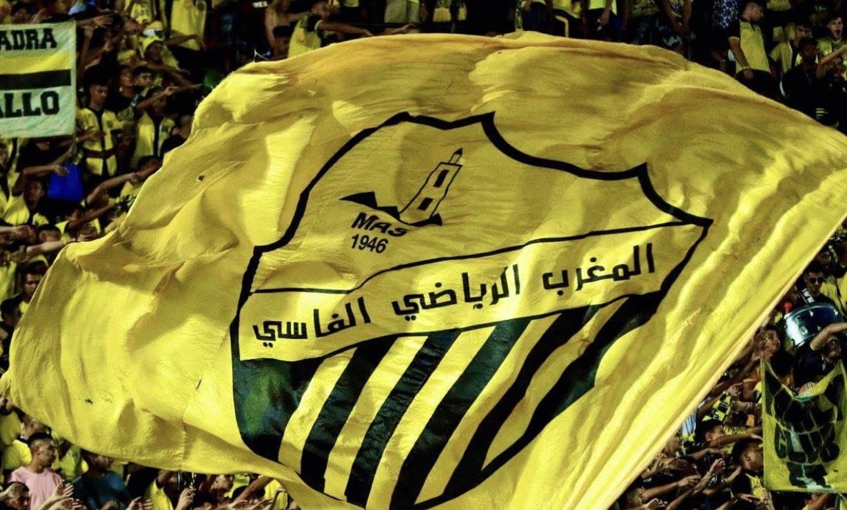 مشجعو فريق المغرب الفاسي يهتفون ويرفعون أعلام ناديهم في المدرجات.
