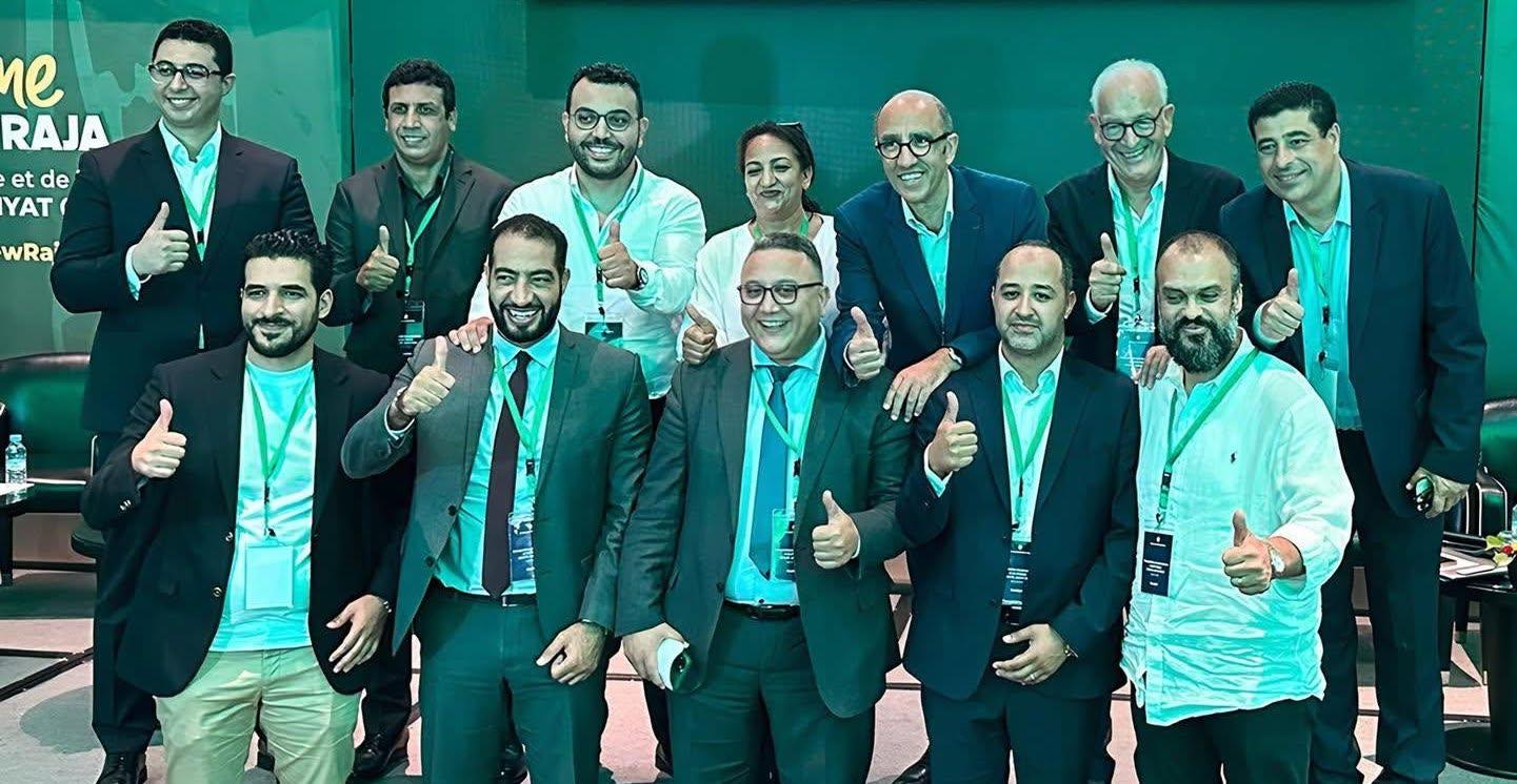الرجاء الرياضي: شعار نادي الرجاء الرياضي على خلفية ملعب كرة قدم.