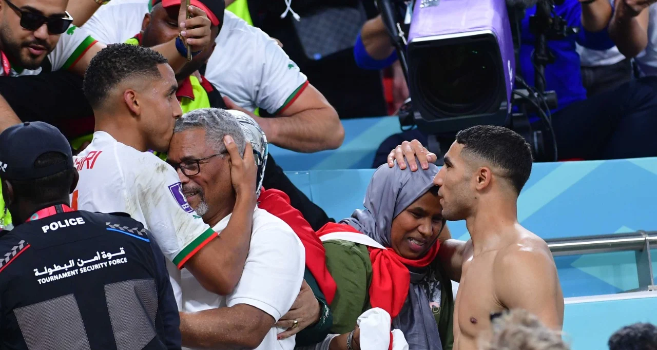 لاعبي المنتخب المغربي يحتفلون مع عائلات أسود الأطلس بعد مباراة حاسمة.