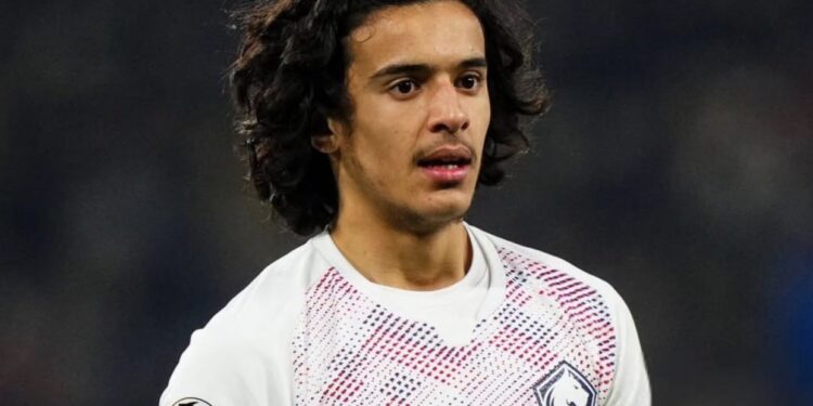اللاعب أيوب بوعدي يرتدي بدلة بيضاء حمراء ويسجل هدفا في مرمى.